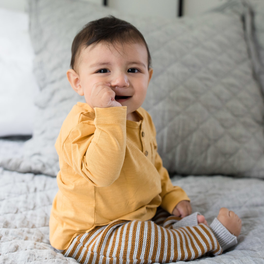 Toddler sitting up on made bed