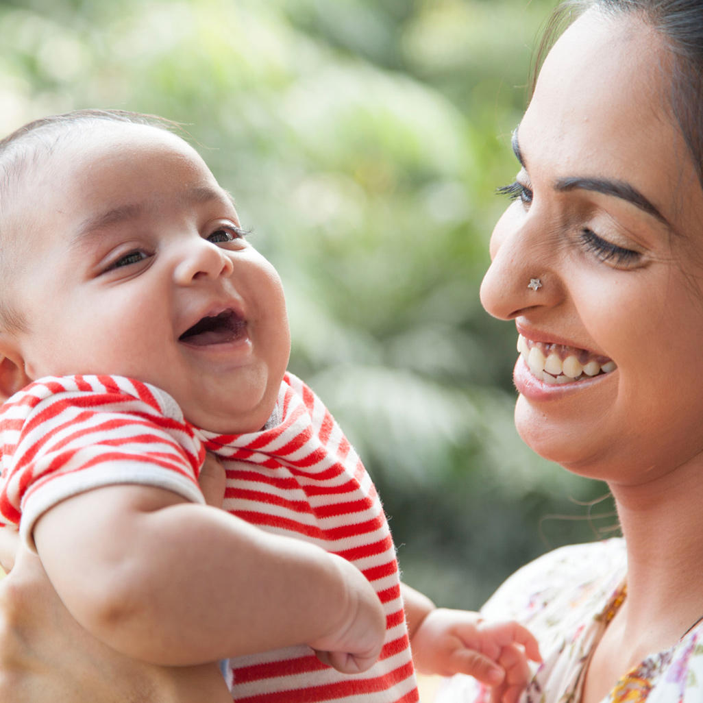 mother and baby laughing while she is holding the baby up high