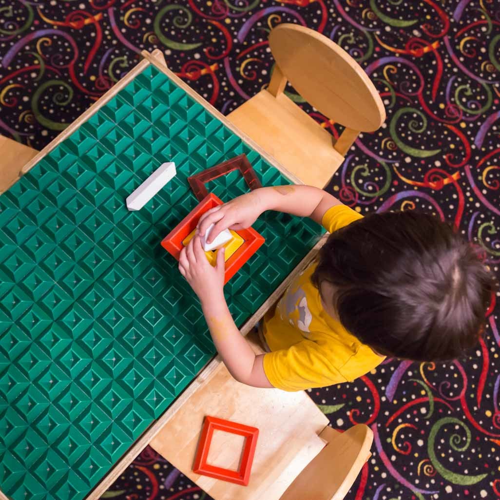 toddler manipulating toy while sitting at table