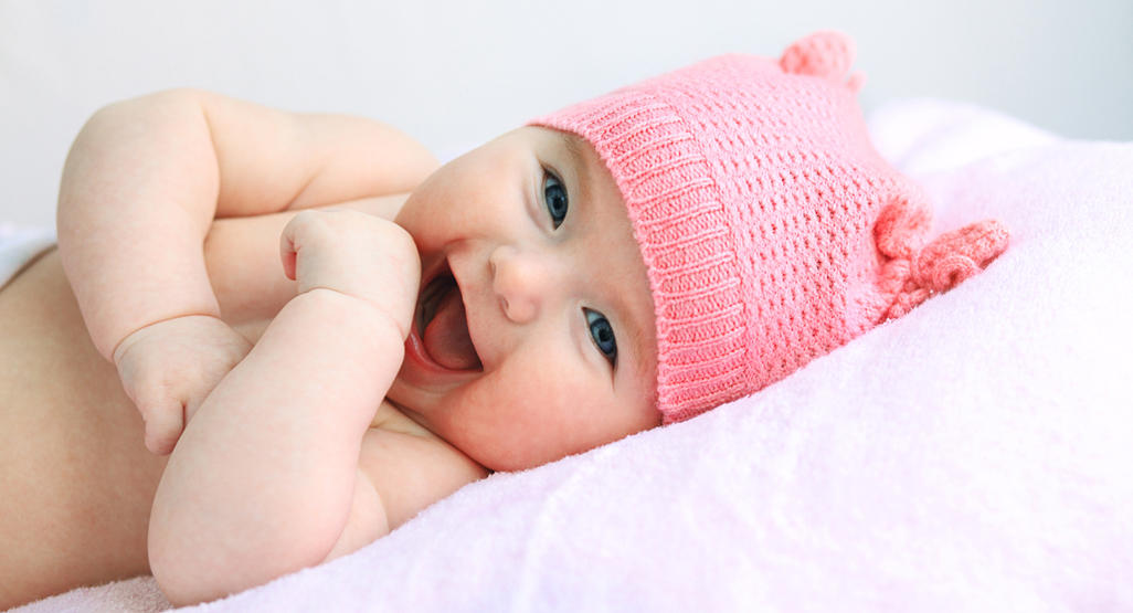 baby in pink hat laughing at camera