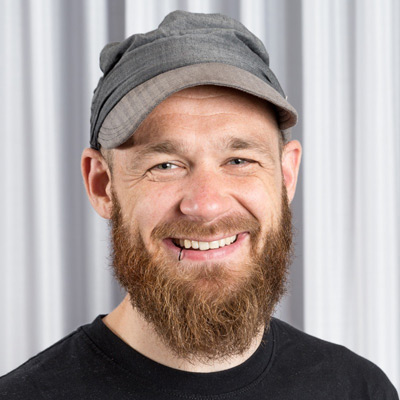 Niels ten Oever. Postdoctoral Researcher, University of Amsterdam. Wearing a grey cap and a black t-shirt.