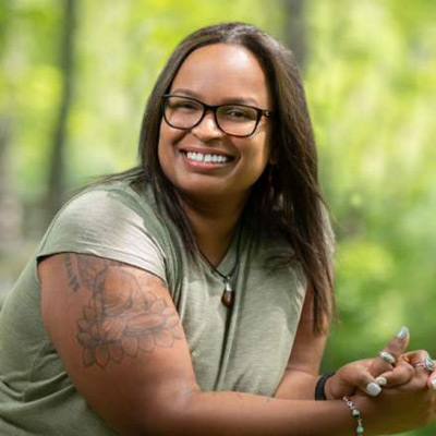 Maria Rodriguez. Faculty Associate, Berkman Klein Center for Internet & Society. Wearing glasses and a green t-shirt, in front of a green / leafy background.