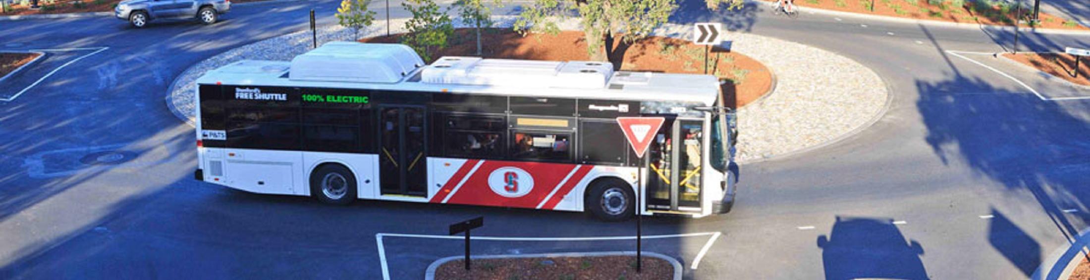 Marguerite bus and bicyclist using a roundabout on campus.