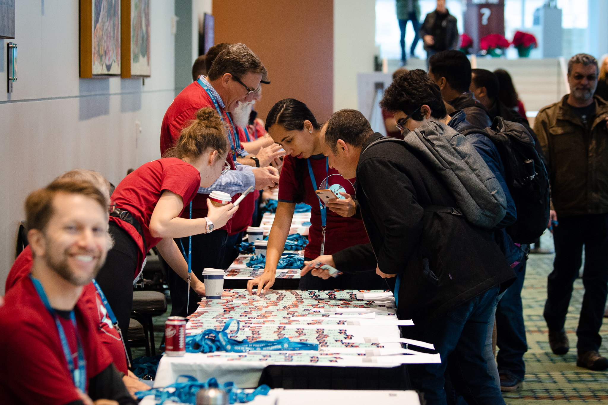 Attendees and volunteers looking at ID badges at registration table at WordCamp US. Photo Credit: Jen Hooks