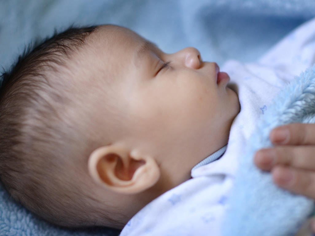 bebé durmiendo con la mano de su madre sobre su pecho