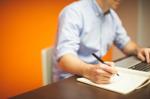 Man Writing In Notebook With Laptop Free Stock Picture