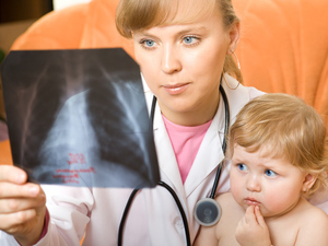 woman doctor holding a baby and looking at x-ray