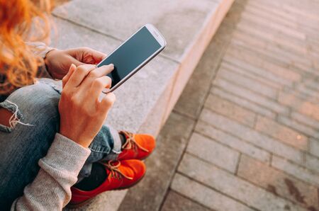 Young female using smartphone outdoors at sunset