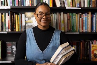 Faridah holding books in a bookshop