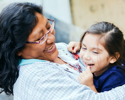 Adult and child laughing and smiling while embracing in a hug.