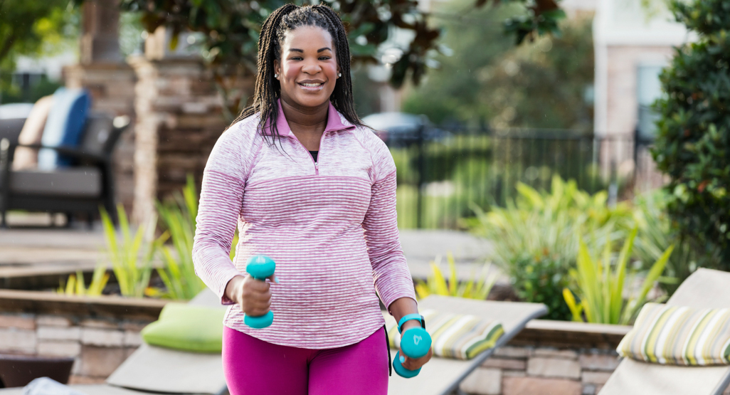 pregnant woman walking while holding hand weights