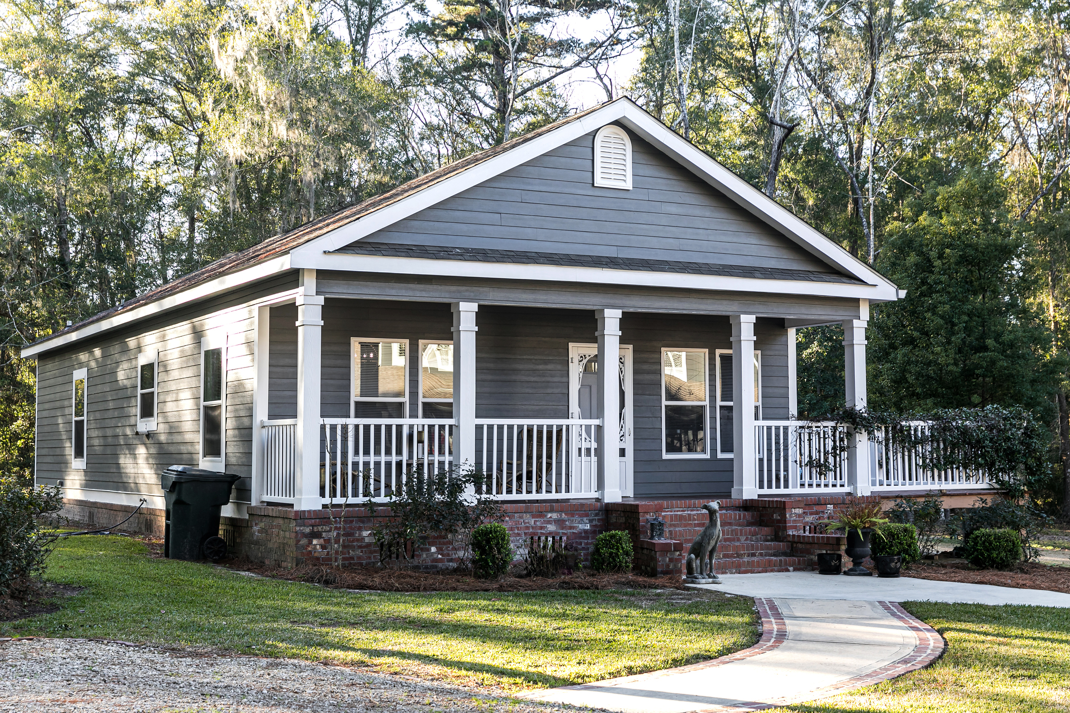 Close up of small blue gray mobile home with a front and side porch with white railing 