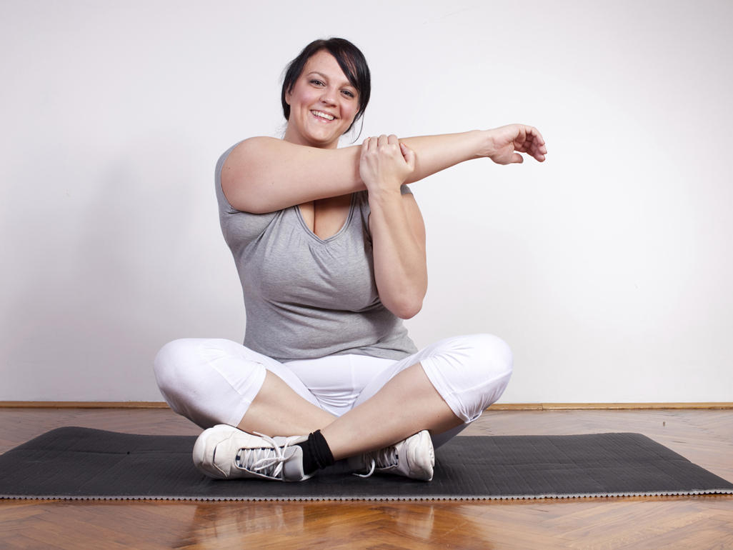 Frau auf einer Yogamatte macht Dehnübungen