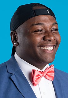 Anderson smiling, wearing a bow tie and a baseball cap