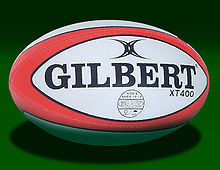 An oval-shaped synthetic ball, white in colour with red trim, adorned with the manufacturer's name