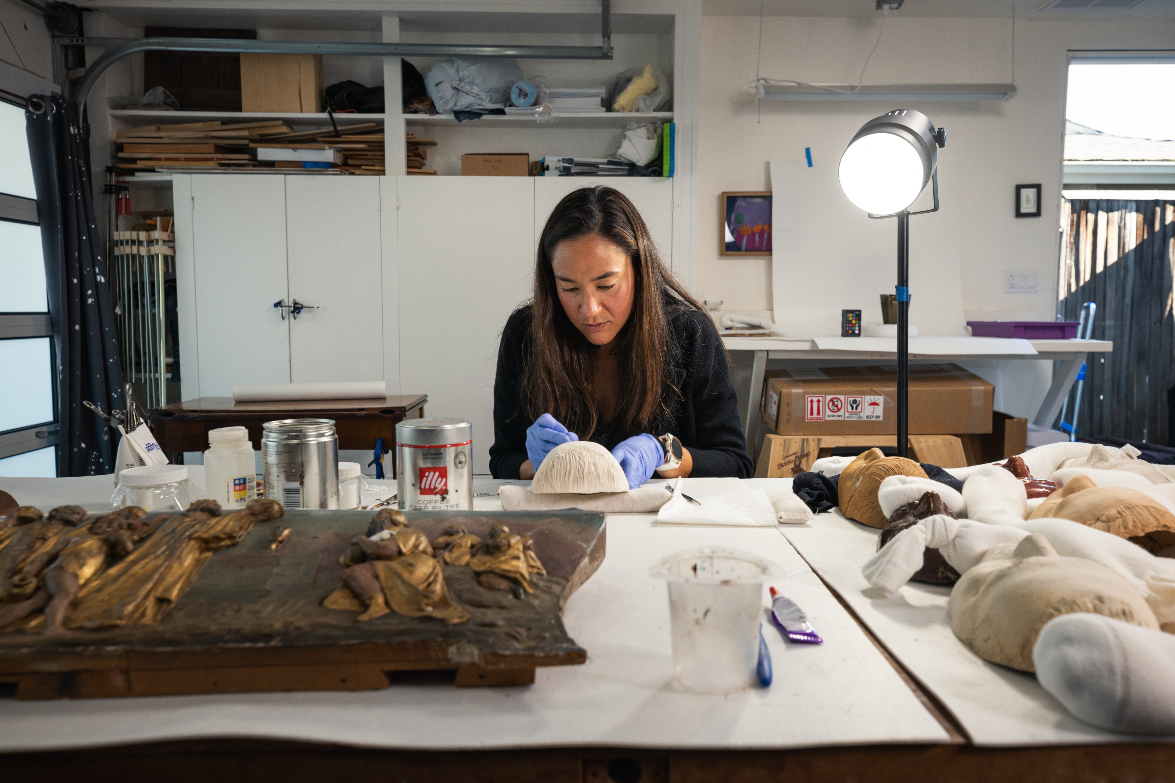 A conservator examines one of the clay masks in her studio. 