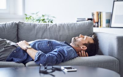 Man lying on couch with eyes closed.
