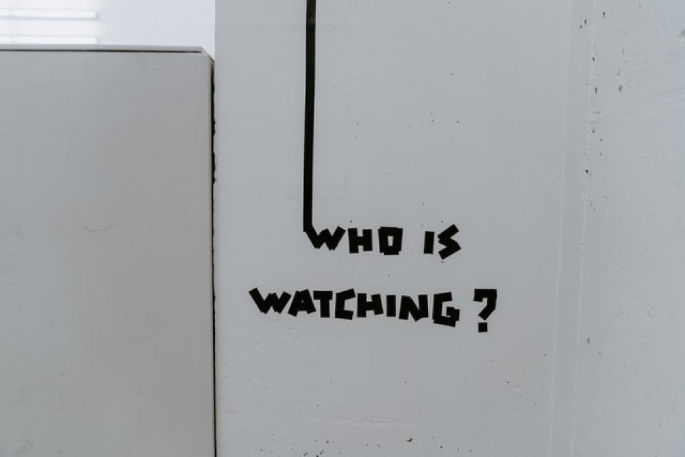 Wall with who is watching painted on.