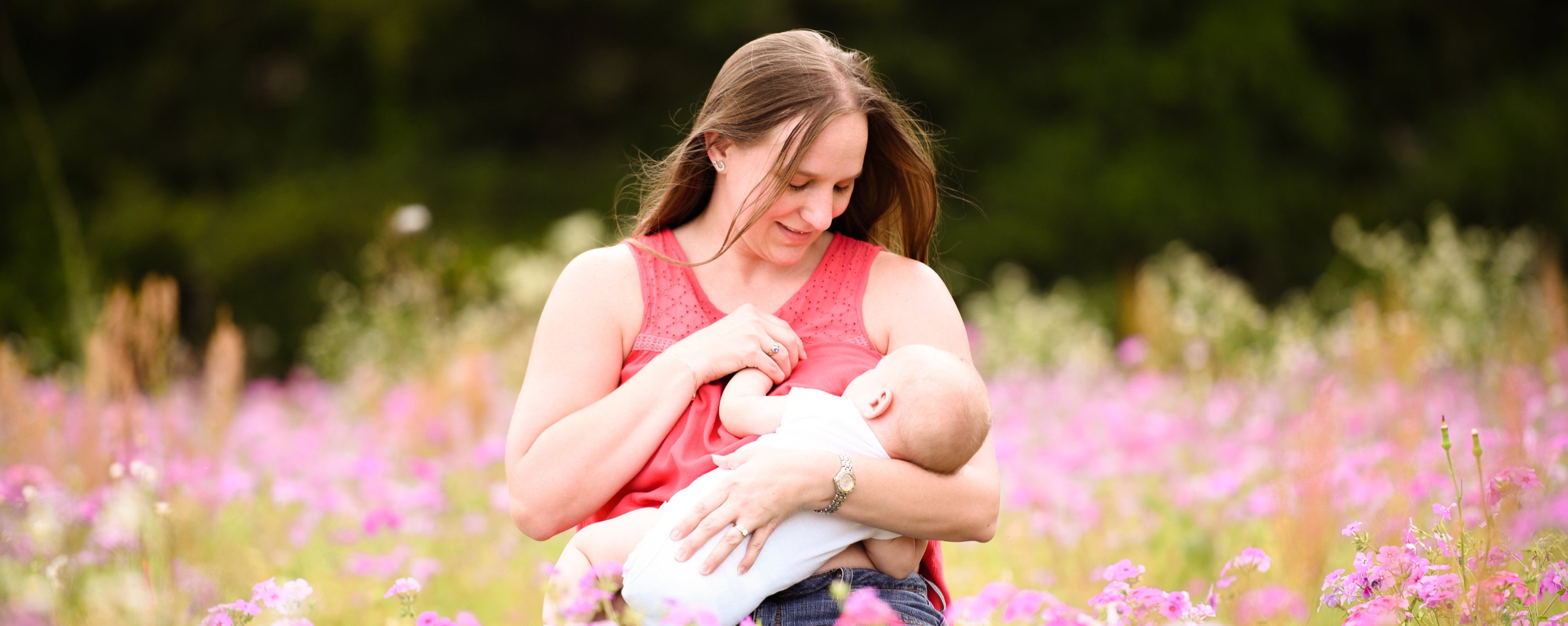 Mother nursing her baby in a beautiful field of spring flowers. 