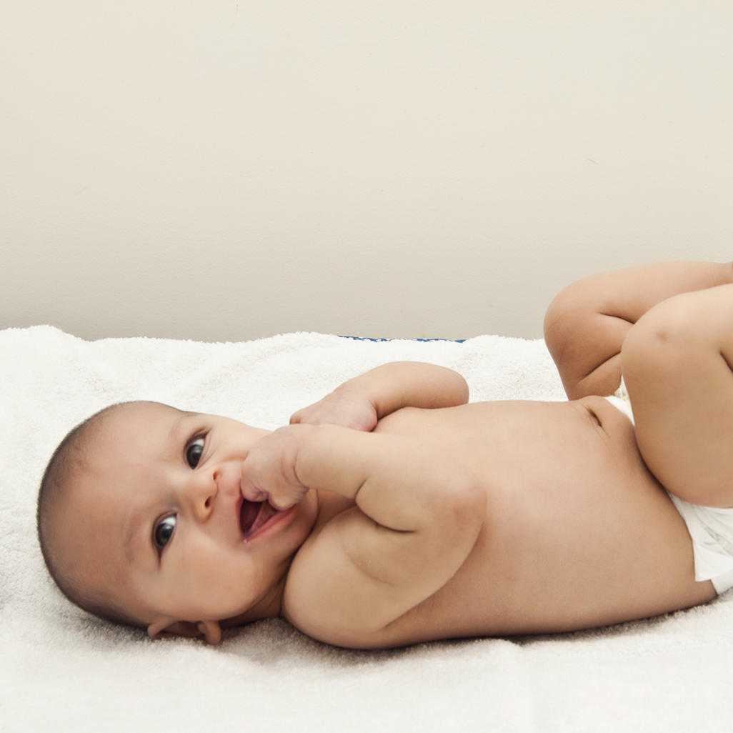 baby laying on its back wearing only a diaper