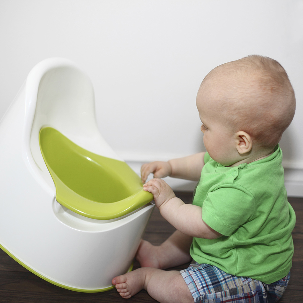 baby sitting on the floor playing with a potty chair