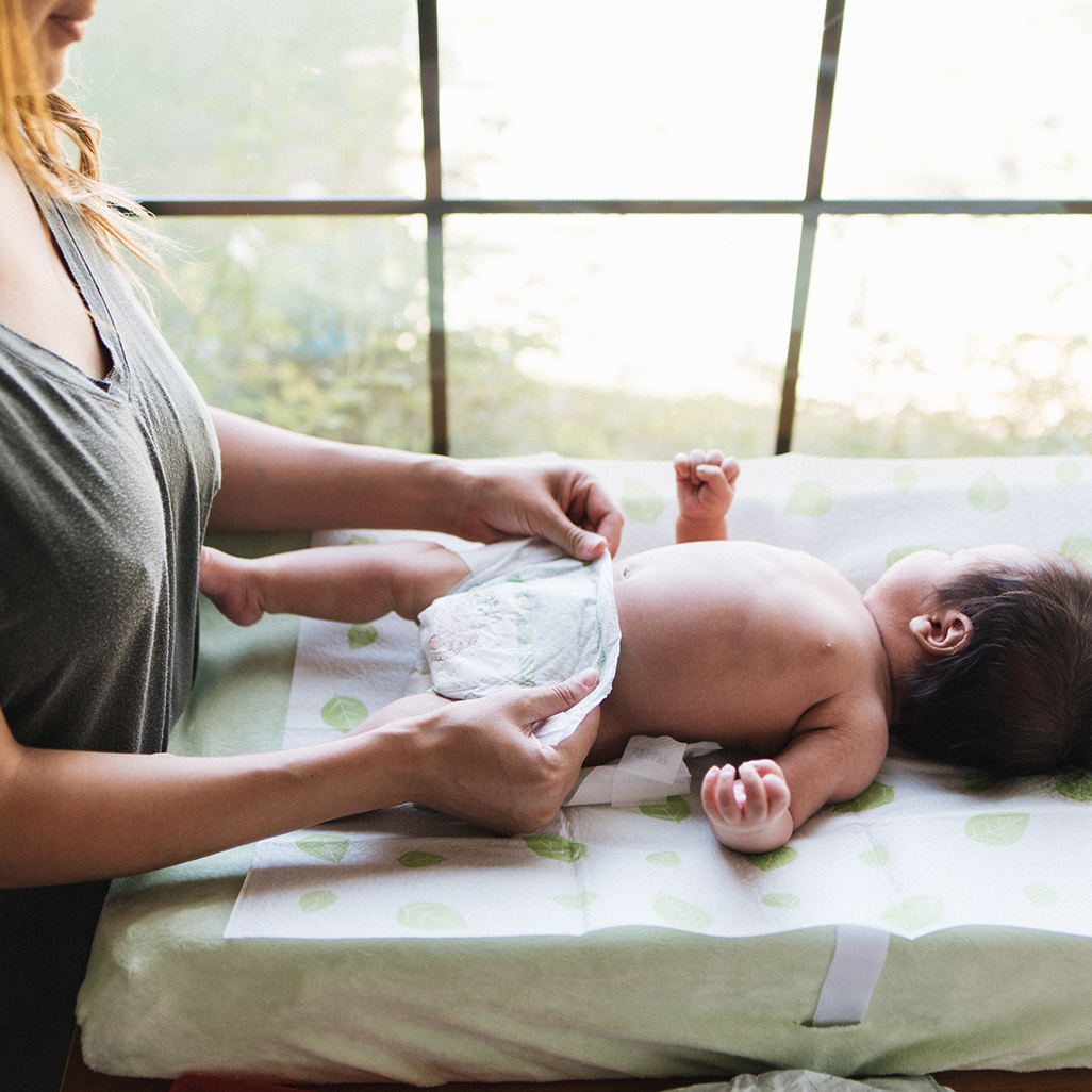 mother changing baby's disposable diaper