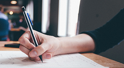 Outstretched arm of person writing with a mechanical pencil.