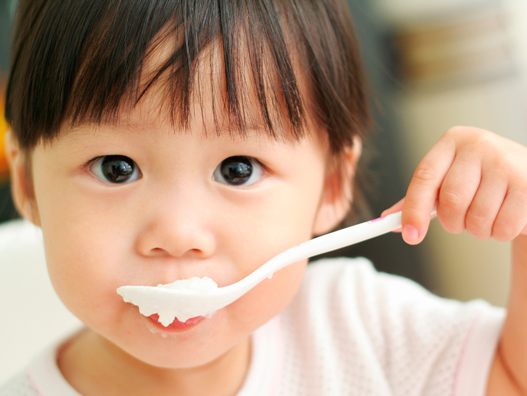 boy feeding himself with a plastic spoon