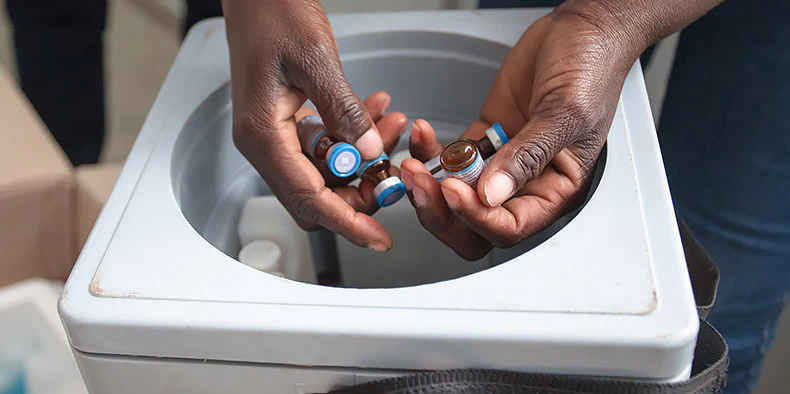 two hands removing vials from a box