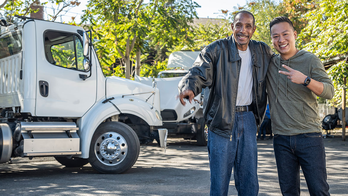 two men looking happy in front of a truck