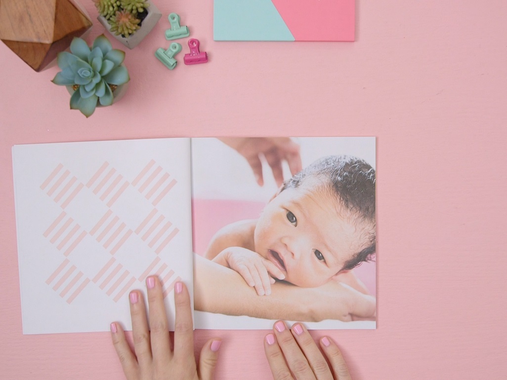 woman's hands holding open page of book with baby image