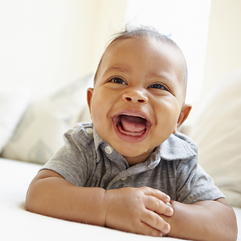 baby laying on tummy with head up smiling