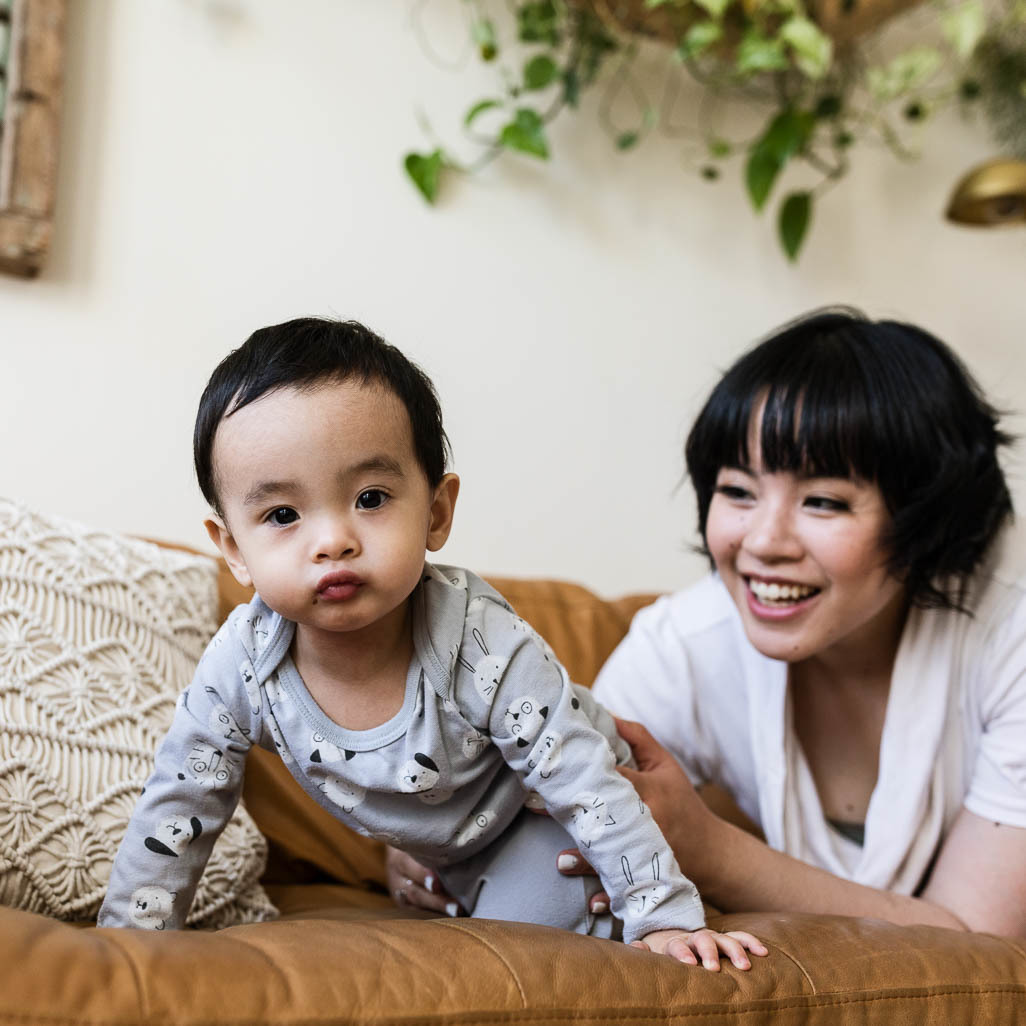 1-year-old crawling on couch with mom watching