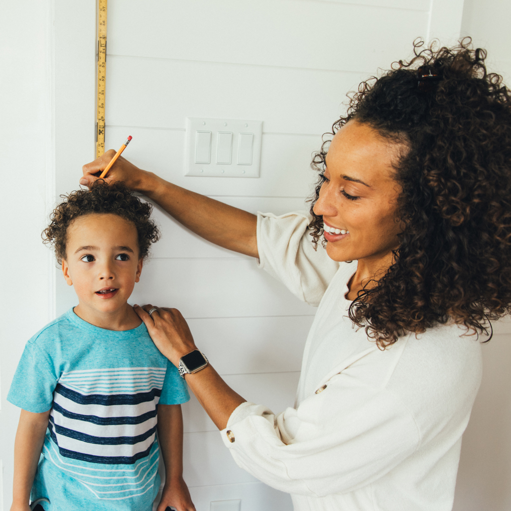 Mom measuring her son's height with a ruler