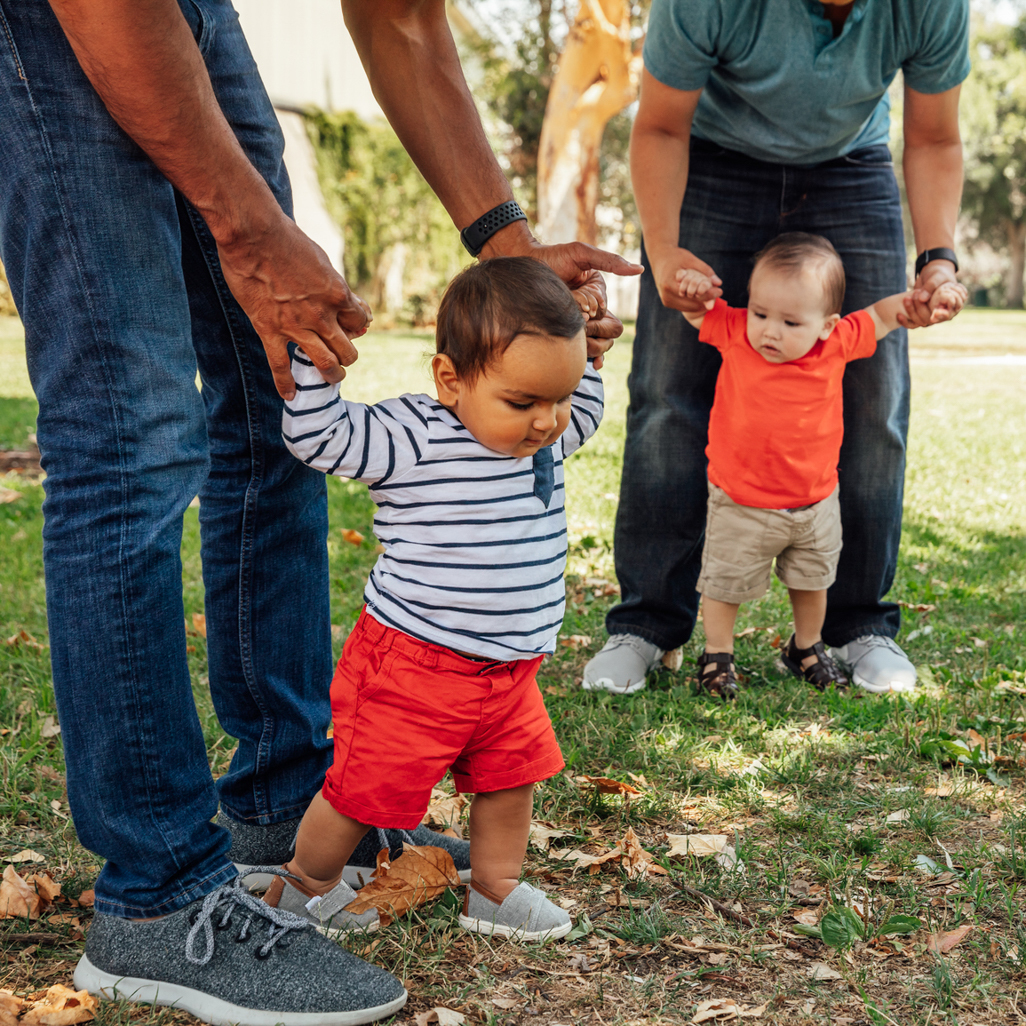 dads with babies holding their hands to help them walk