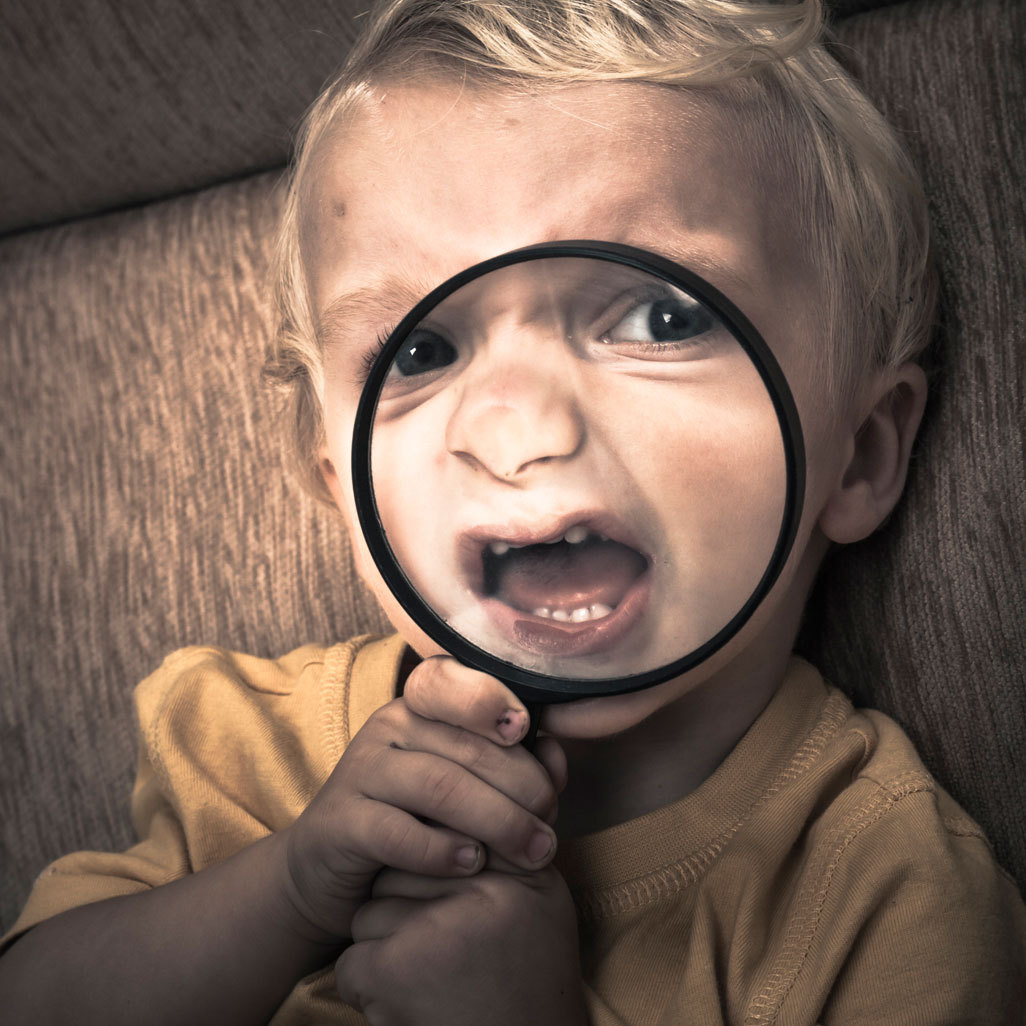 child holding a magnifying glass over its mouth