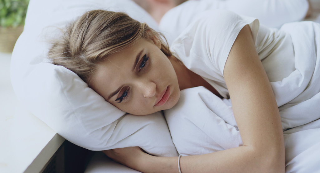 mujer en la cama abrazándose a la almohada