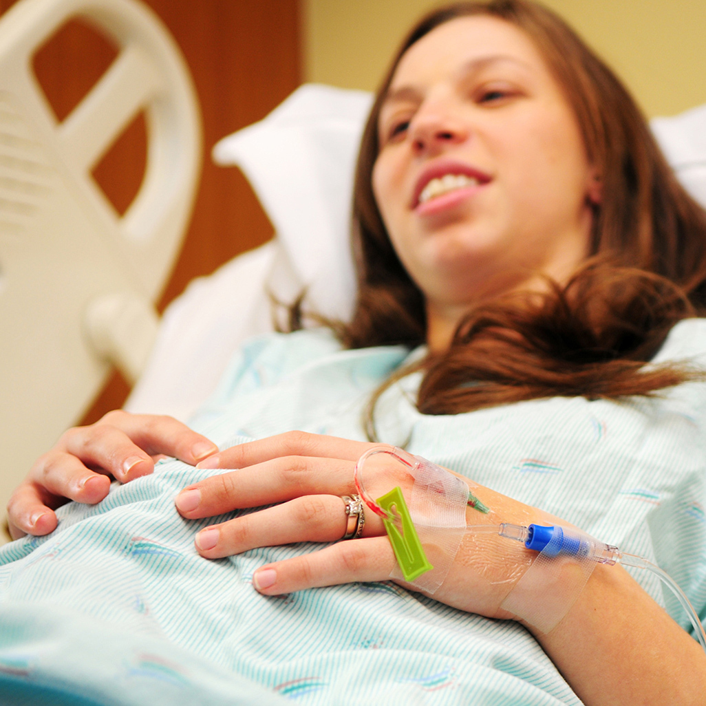 pregnant woman laying on a hospital bed with I.V. needle attached to her hand