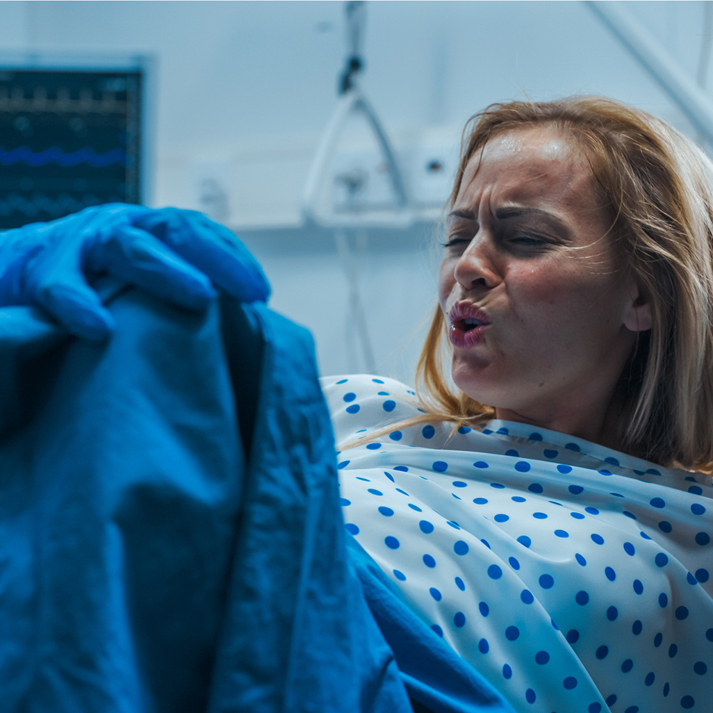 woman pushing while in active labor while partner holds her hand