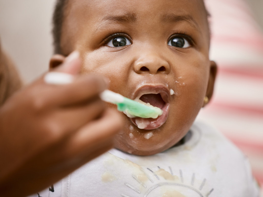 baby being spoon fed with messy face