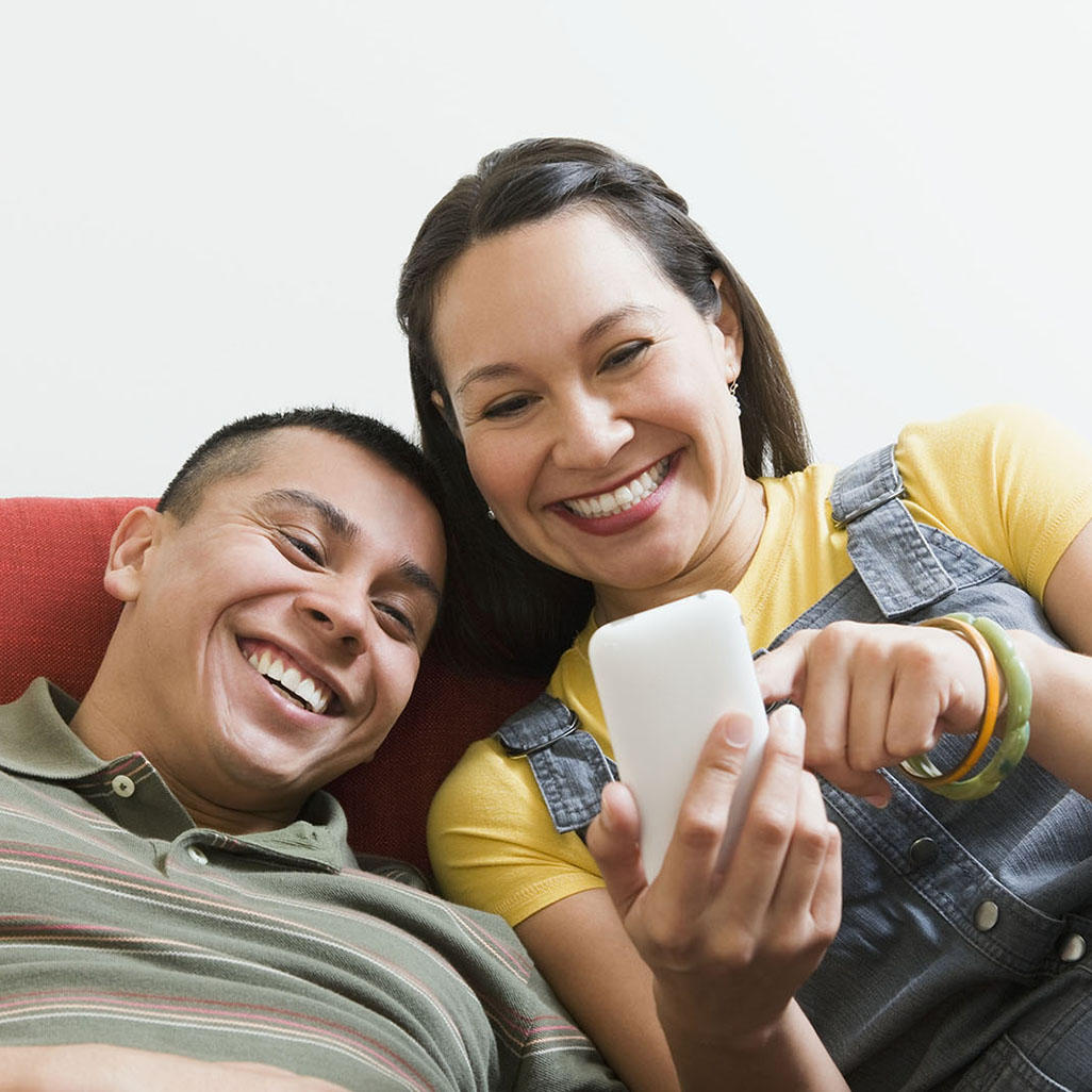 man and woman looking at a phone and both smiling