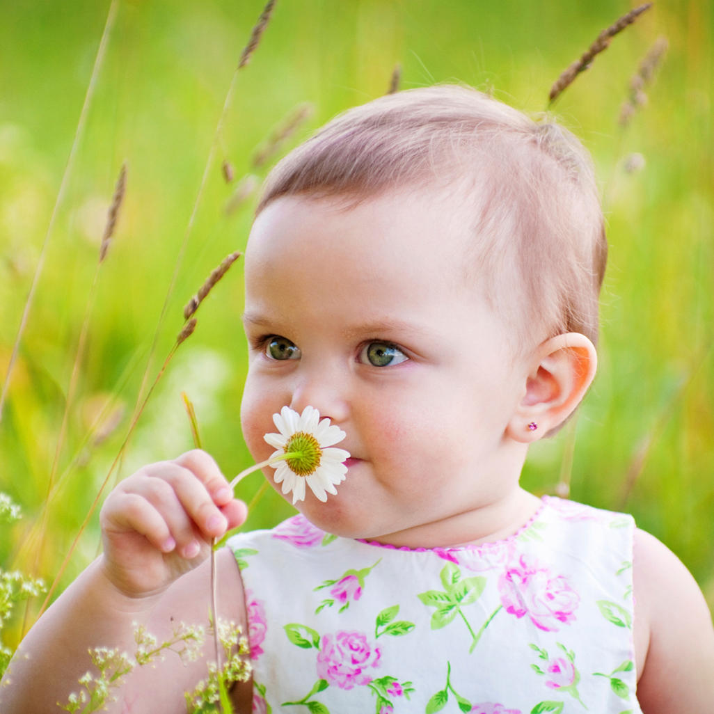 baby holding a flower to her nose