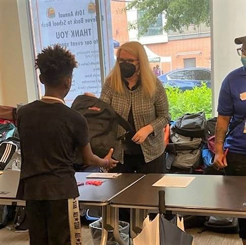 HRSA Administrator Carole Johnson hands out backpack to young boy