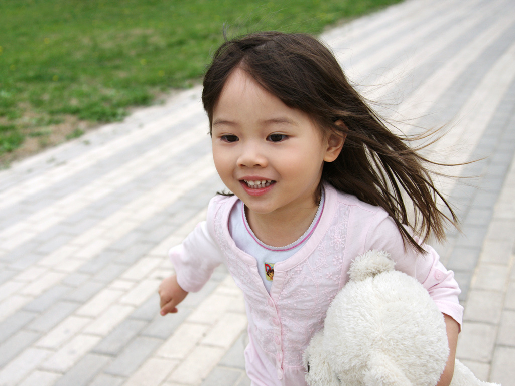 happy child with her teddy bear running outside