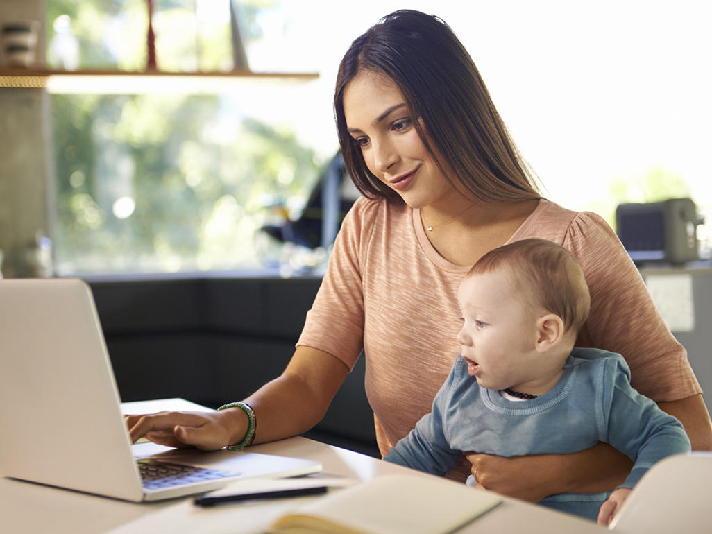 mother with a child in her lap typing on a laptop