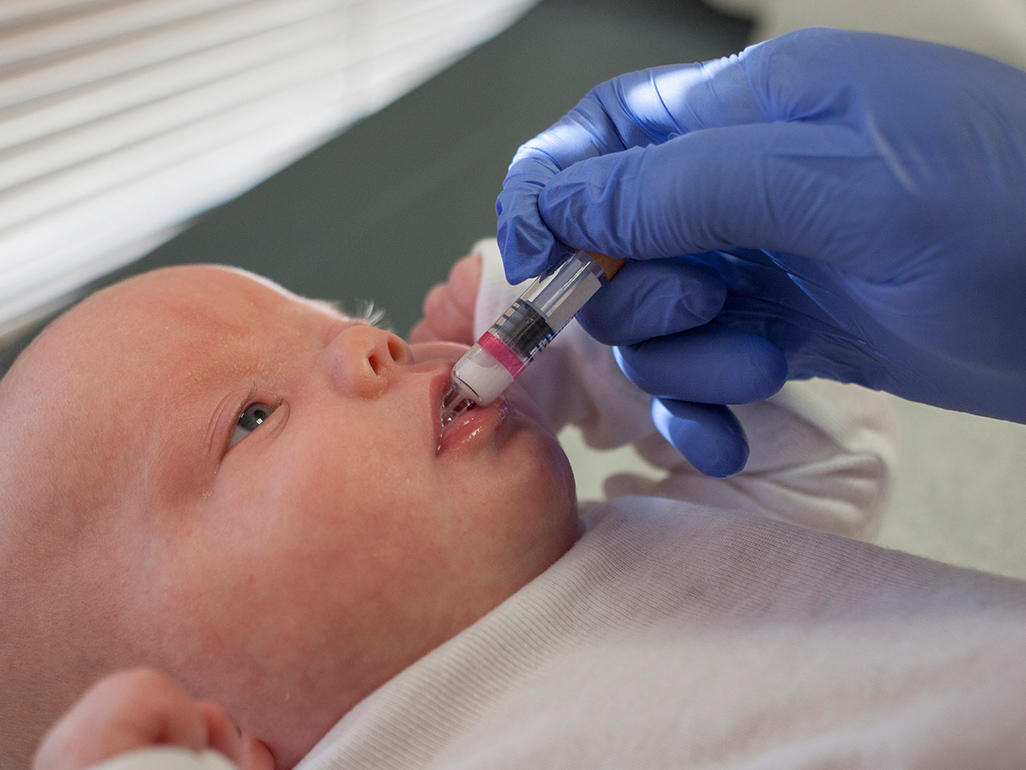 baby receiving a medicine through mouth from a syringe