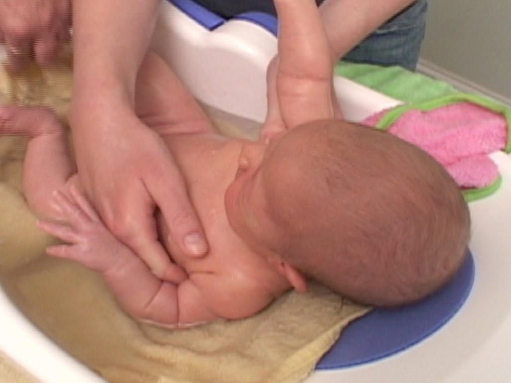 baby in tub being bathed by adult
