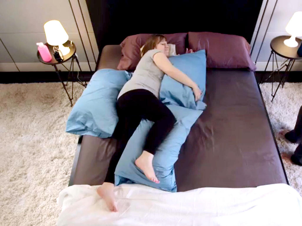 Schwangere Frau liegt mit mit Kissen gestützt im Bett