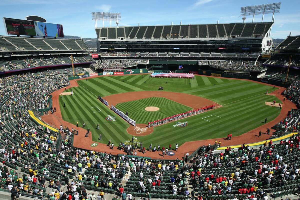 FILE - The Los Angeles Angels and Oakland Athletics stand for the national anthem at the Oakland Coliseum prior to an opening day baseball game in Oakland, Calif., in this Thursday, March 29, 2018, file photo.Major League Baseball instructed the Athletics to explore relocation options as the team tries to secure a new ballpark it hopes will keep the club in Oakland in the long term. MLB released a statement Tuesday, May 11, 2021, expressing its longtime concern that the current Coliseum site is “not a viable option for the future vision of baseball.” (AP Photo/Ben Margot, File)