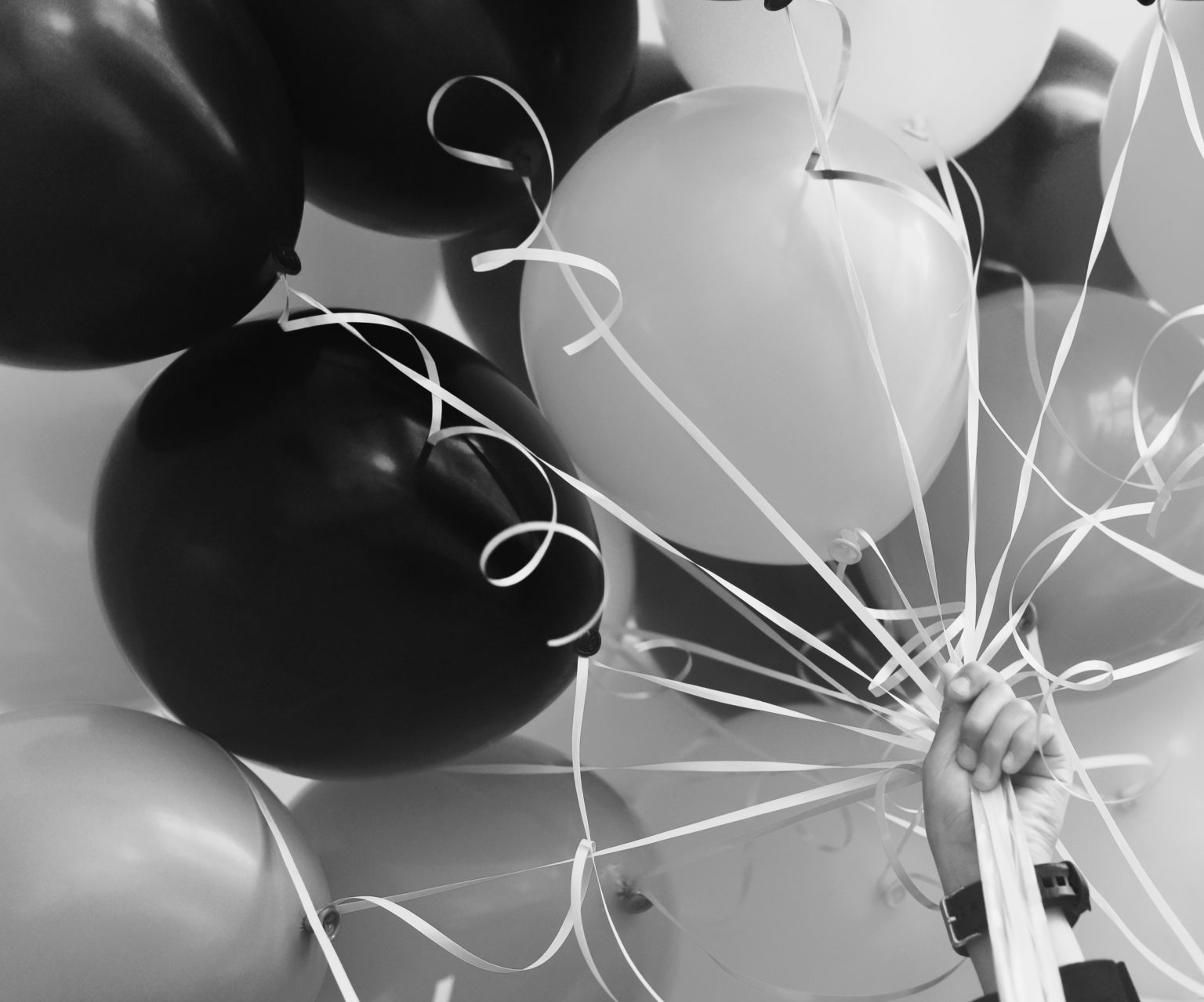 Black and white image of a hand holding a bunch of balloons. Photo contributed by Rich Tabor to the WordPress Photo Directory.